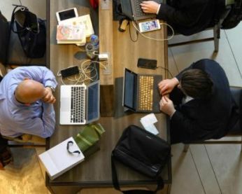 Vue aérienne de personnes assises à une table et travaillant sur leur ordinateur portable