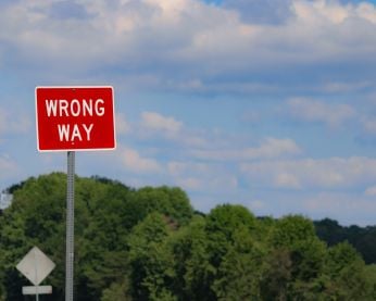 Landscape photo with a red sign that reads "Wrong way"
