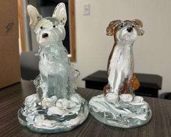 Two glass-blown dogs. On the left is a white husky called Moose and on the right is a floppy-eared husky called Floppy.