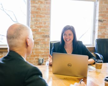 Two people meeting at a boardroom table.