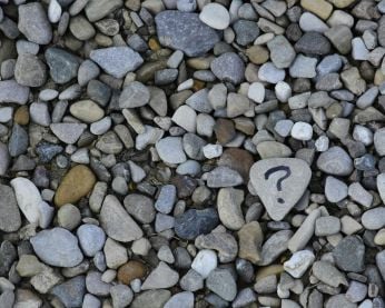 A close up of stones and one has a question mark drawn on it.