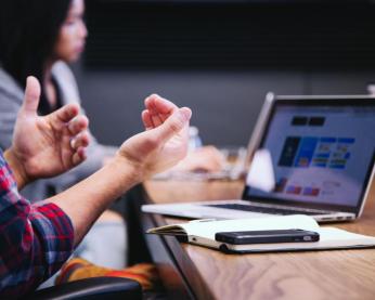 Person with a laptop talking in a meeting