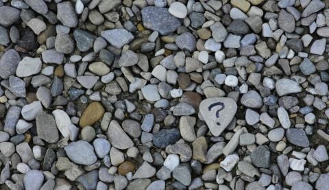 A close up of stones and one has a question mark drawn on it.