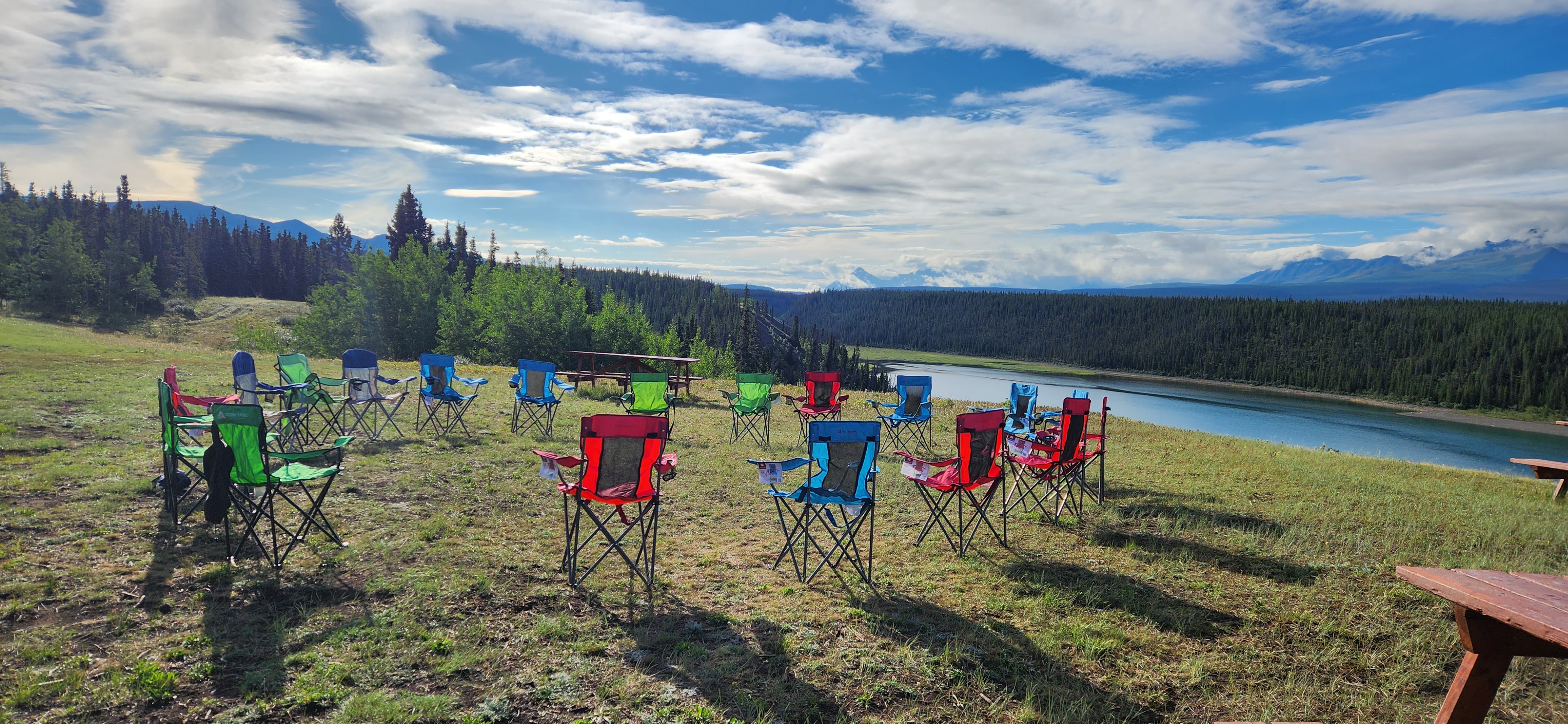 A circle of camp chairs overlooks the water at Shakat Tun wilderness camp near Haines Junction