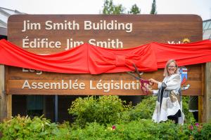 La fille de Jim Smith, Marilyn Smith, coupe le ruban du nouveau panneau de l’édifice Jim-Smith. Photo : Gouvernement du Yukon