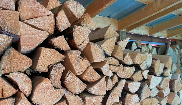 A pile of split firewood piled in a shed.