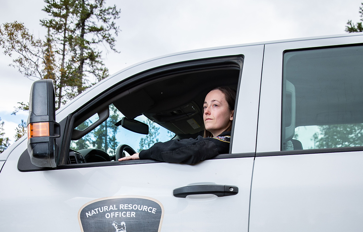 A natural resource officer looking out the window of a pickup truck.
