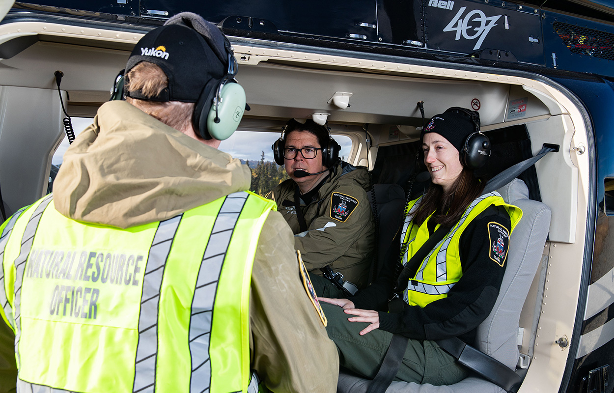 Natural resource officers discussing in the passenger cabin of a helicopter.