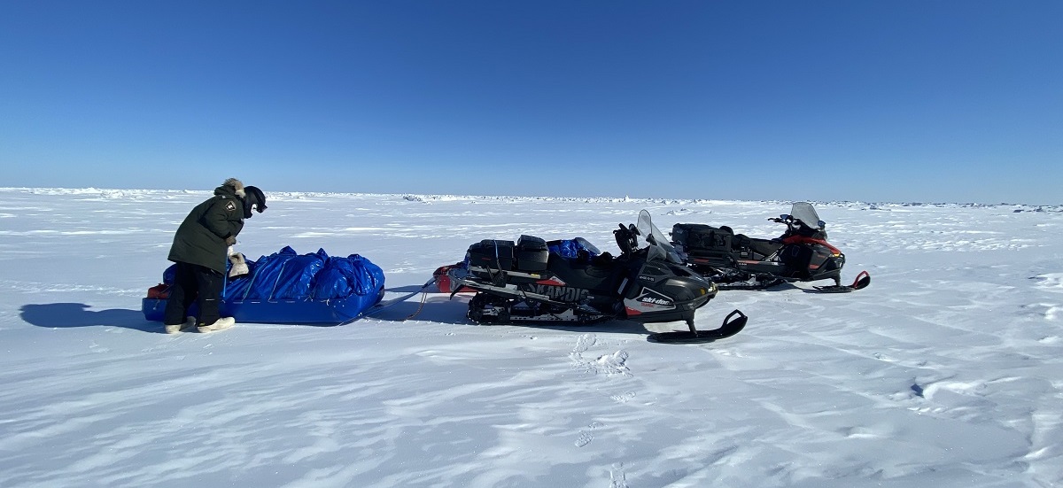 A conservation officer secures a load to a snowmobile.