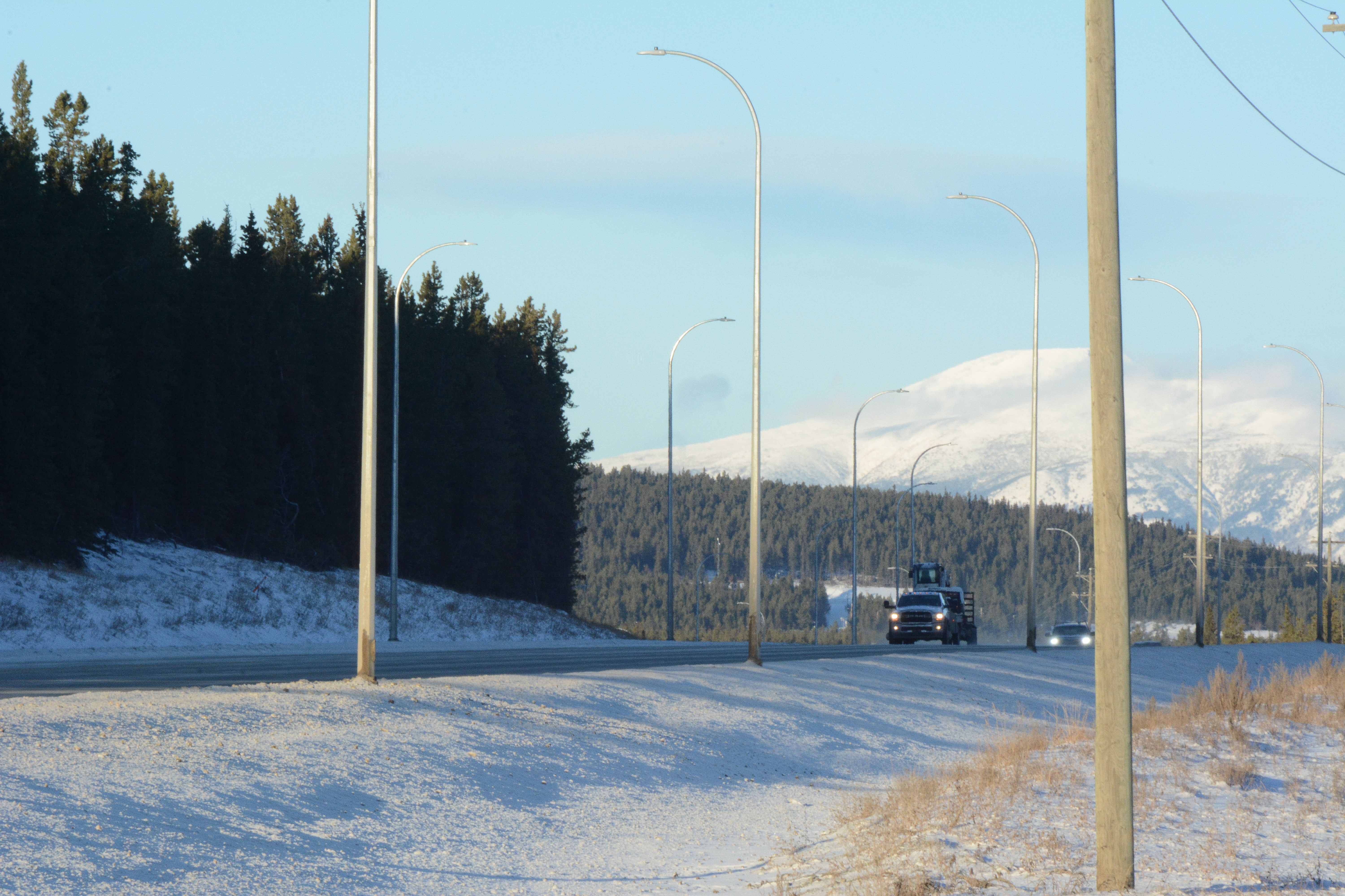View of vehicles driving on the Alaska Highway from an active transportation path.