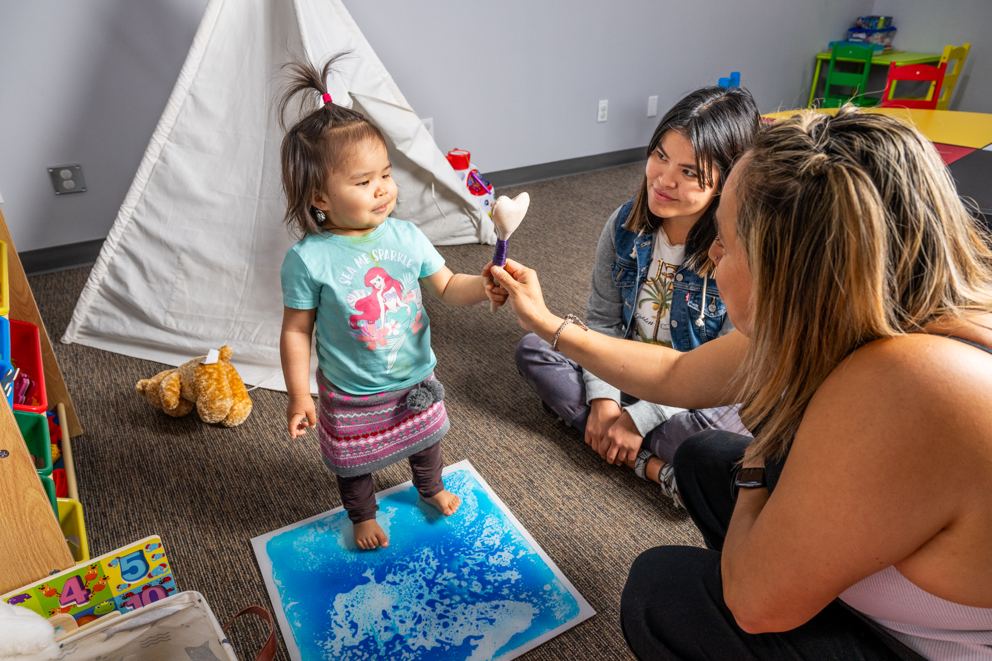 Child and two adults playing with toys at the Council of Yukon First Nations' Family Preservation Services 