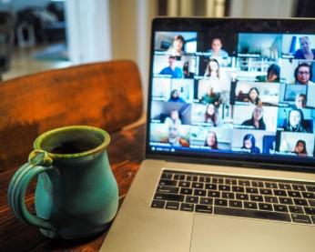A mug and laptop screen showing a Zoom call