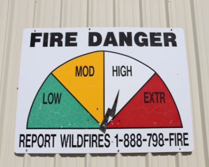 Fire danger sign showing low, moderate, high, extreme with needle pointing to high