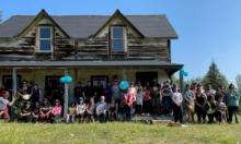 Attendees pose for a group photo in front of the Cadzow House at Gindèhchik / Rampart House. Photo credit: Government of Yukon.
